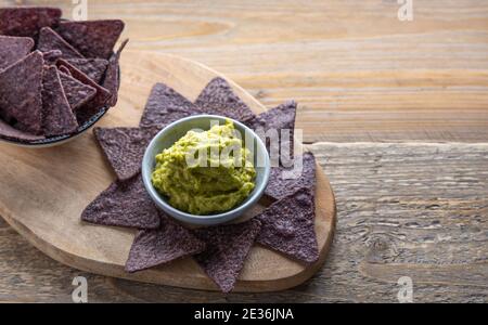 Blaue Mais Tortilla Chips mit hausgemachten Guacamole auf der Seite. Stockfoto