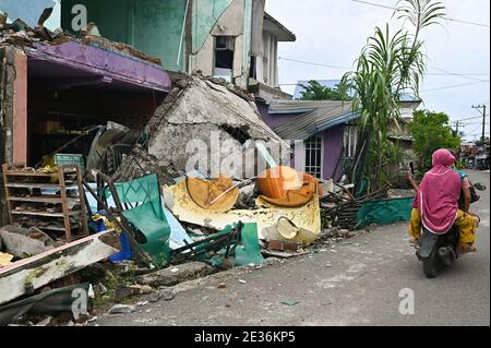 Mamuju, Indonesien. Januar 2021. Ein Autofahrer fährt an einem beschädigten Gebäude vorbei. Nach dem Erdbeben der Stärke 6.2, das am 15. Januar 2021 eintraf und mindestens 56 Menschen tötete, wurden Hunderte verletzt und Tausende von Einwohnern evakuiert. Kredit: SOPA Images Limited/Alamy Live Nachrichten Stockfoto