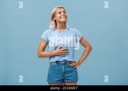 Nettes Mädchen mag essen nach dem Training zufrieden und gefüllt nach dem Abendessen. Porträt von zufrieden attraktive blonde junge Frau berühren Bauch heben Stockfoto