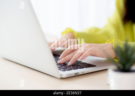 Nahaufnahme der Hand junge asiatische Geschäftsfrau arbeiten auf Laptop-Computer auf dem Schreibtisch im Home Office, freiberuflich suchen und tippen auf Notebook auf dem Tisch, Frau Stockfoto