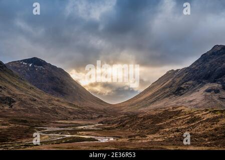 Atemberaubende Landschaftsaufnahme im Glencoe Valley in den schottischen Highlands Mit Bergketten in dramatischer Winterbeleuchtung Stockfoto