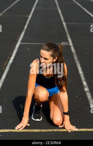 Außenaufnahme einer jungen Sportlerin, die auf der Rennstrecke läuft. Profi-Sportlerin beim Lauftraining. Stockfoto