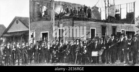 WILMINGTON MASSAKER North Carolina 10 November 1898. Mob posiert mit Waffen außerhalb der ausgebrannten Ruinen des Tagesrekord Stockfoto