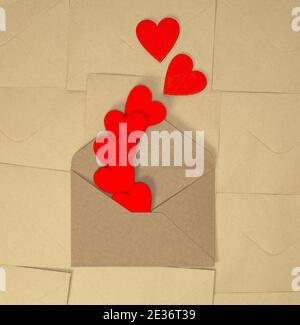 Valentines Day Bastelumschlag mit roten Herzen auf braunem einfarbigem Papier Hintergrund, romantische Liebe Design Draufsicht, Kopierraum Stockfoto