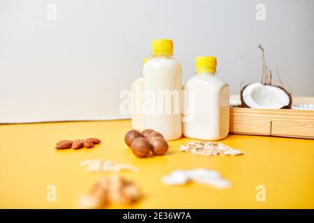 Alternative Sorten veganer Milch in Flaschen auf gelbem Hintergrund, verschiedene vegane Milch und Zutaten auf pflanzlicher Basis, nicht-Milchmilch, alternative Milch, Stockfoto