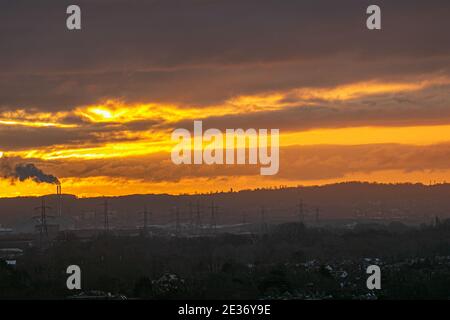 WIMBLEDON LONDON, GROSSBRITANNIEN 17. JANUAR 2021. Rauchwolken aus einem Kamin und Sendetürmen eines Kraftwerks, die an einem kalten Morgen gegen den farbenfrohen Sonnenaufgang über Wimbledon schillerten. Kredit: amer ghazzal/Alamy Live Nachrichten Stockfoto