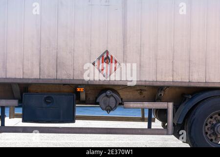 LKW zum Transport von Schüttgütern mit Platten und Gefahrenetiketten durch die Ladung von spontan brennbaren Feststoffen. Stockfoto