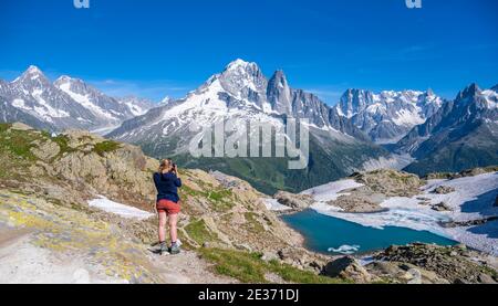 Junge Frau fotografiert Bergpanorama, Lac Blanc, Berggipfel, Grandes Jorasses und Mont Blanc Massiv, Chamonix-Mont-Blanc, Haute-Savoie Stockfoto