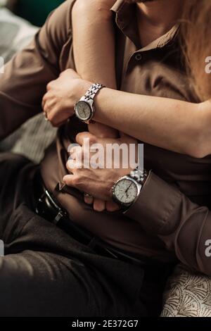 Hände des romantischen Paares umarmen und halten die Hände zusammen. Close up Hände mit Uhren mit Metall Silber Armband, Armband. Frau umarmt einen Mann von Stockfoto