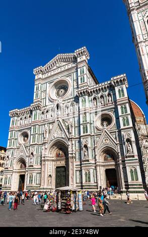 Voller Blick auf die Kathedrale Santa Maria del Fiore in der Piazza del Duomo. Viele Leute auf dem Platz kommen an einem Souvenirstand vor dem Hotel vorbei... Stockfoto