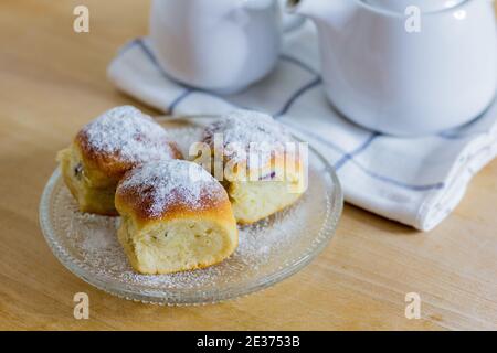 Süße Brötchen 'Austrian buchteln' oder tschechisch sowie slowakisch 'Buchty' bestreut mit Zucker auf Holztisch mit Tee Stockfoto