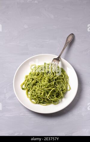 Spaghetti Pasta mit grünem Pesto von Grünkohl, Walnüssen, Knoblauch und Olivenöl auf grauem Hintergrund. Draufsicht. Leckeres hausgemachtes Essen Stockfoto