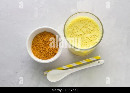 Goldene Milch mit Kurkuma im Glas auf grauem Steingrund. Gesundes natürliches Energietrink. Selektiver Fokus Stockfoto