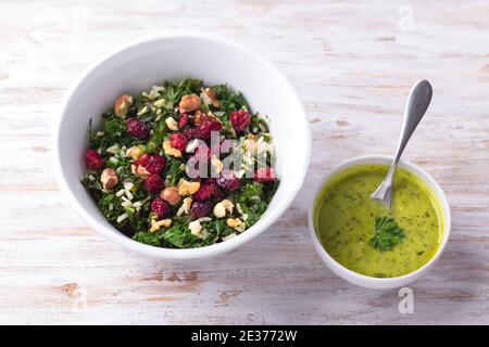 Warmer Grünkochsalat mit braunem Reis, getrockneten Preiselbeeren und Nüssen auf hellem Hintergrund. Köstliche gesunde Ernährung Lebensmittel Stockfoto