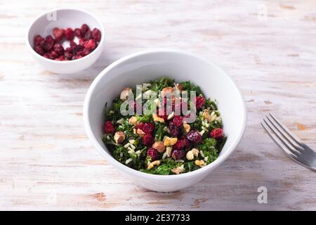 Warmer Grünkochsalat mit braunem Reis, getrockneten Preiselbeeren und Nüssen auf hellem Hintergrund. Köstliche gesunde Ernährung Lebensmittel Stockfoto