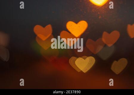 Valentine-Konzept, Stadtlichter sind verschwommen, mit einem herzförmigen Bokeh Hintergrund, Auto auf der Straße in der Nacht, Liebe Symbol. Stockfoto