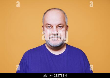 Porträt von älteren Mann mit grau weißen Haaren und Bart vor orangefarbenem Studiohintergrund Stockfoto