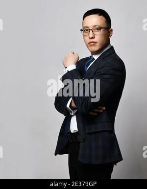 Junge asiatische Geschäftsmann Experte in formelle Jacke, Krawatte und Brille steht Seite an Kamera mit Armen an Brust gekreuzt Stockfoto