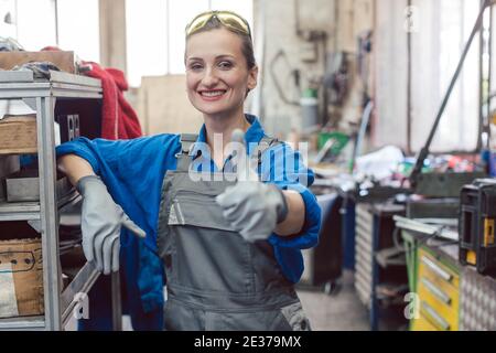 Eine Arbeiterin in der Metallwerkstatt zeigte den Daumen nach oben Stockfoto