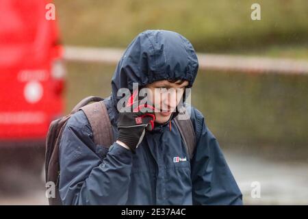 London, Großbritannien. Januar 2021. Ein Mann, der mit seinem Handy spricht, während er unter dem Regen läuft. Quelle: Steve Taylor/SOPA Images/ZUMA Wire/Alamy Live News Stockfoto