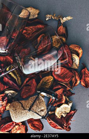 Nahaufnahme von zwei Vintage-Stielgläsern und einem Sektkorken vor einem Hintergrund aus trockenen Rosenblättern. Helles Urlaubskonzept in orange und gelbem Colo Stockfoto