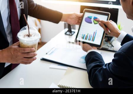 Menschen, die Kaffee halten und schauen Sie sich Business Graph auf dem Tablet, sprechen, planen und diskutieren Stockfoto