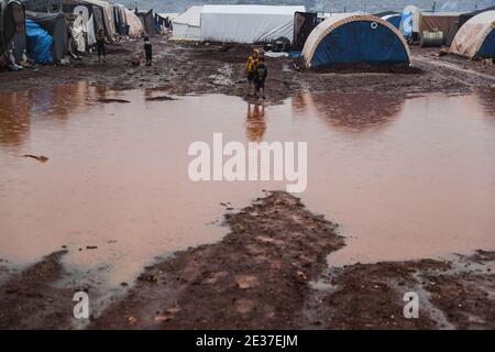 Kafr Aruq, Syrien. Januar 2021. Syrische Kinder stehen im überfluteten Tal Amin Lager für Binnenvertriebene, in der Nähe des Dorfes Kafr Aruq. Die Flüchtlingslager im Norden des Gouvernements Idlib sind von extremem Winterwetter bedroht, da sie in den vergangenen Tagen nach heftigen Regenfällen überflutet wurden. Quelle: Anas Alkharboutli/dpa/Alamy Live News Stockfoto