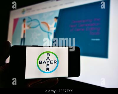 Person mit Smartphone mit Logo des deutschen Unternehmens Bayer AG, einem multinationalen Pharmaunternehmen. Konzentrieren Sie sich auf den Bildschirm des Mobiltelefons. Stockfoto