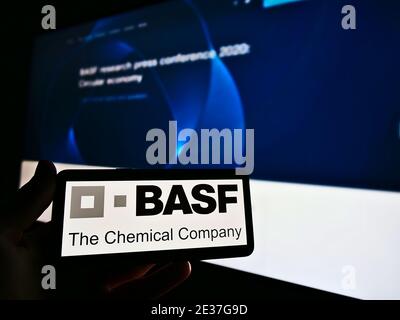 Person mit Smartphone mit Logo des in der chemischen Industrie tätigen deutschen multinationalen Unternehmens BASF SE. Konzentrieren Sie sich auf den Bildschirm des Mobiltelefons. Stockfoto