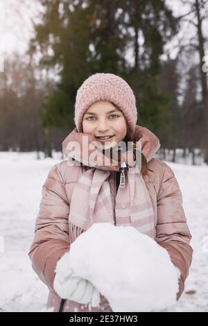 Vertikale Taille bis Porträt von lächelnd Teenager-Mädchen mit Schnee Und die Kamera betrachten, während Sie im Winter draußen spazieren gehen Stockfoto