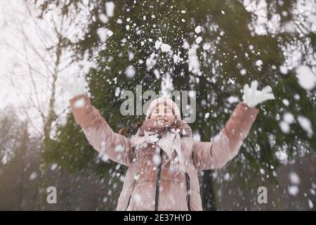 Waist up Porträt von glücklich verspielt Mädchen Schnee werfen, während genießen Spaziergang im Winterwald im Freien, kopieren Raum Stockfoto