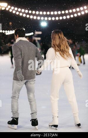 Ein paar Liebhaber halten die Hände auf der Eisbahn im Freien in der Winterzeit. Weihnachten Sport Freizeit Urlaub Stockfoto