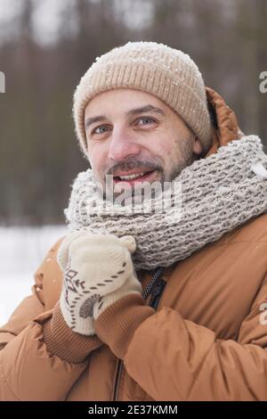 Vertikale Porträt von bärtigen reifen Mann im Winter im Freien tragen Strickmütze und Jacke, während sie die Kamera überzogen anlächeln Schnee Stockfoto