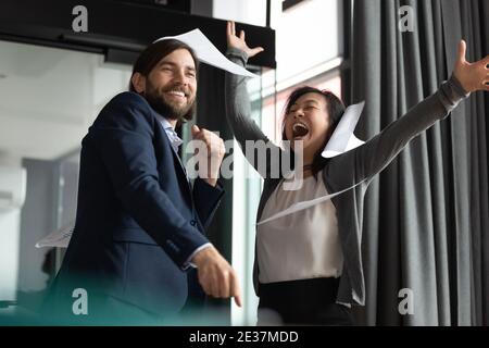 Überglücklich junge 30er Jahre Geschäftsmann feiert Erfolg mit reifen koreanischen Kollegen. Stockfoto