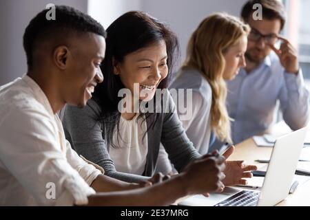 Glückliche alte koreanische Geschäftsfrau arbeitet am Computer mit afrikanischen Kollegen. Stockfoto