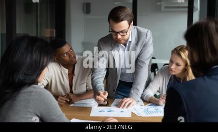 Qualifizierte junge Führungskraft, die Verkaufsdaten bei einem Brainstorming analysiert. Stockfoto