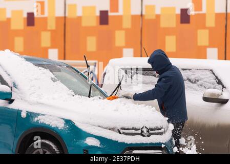 Moskau. Russland. Winter 2020. Der Fahrer räumt dem Auto Schnee. Bei starkem Schneefall in Moskau. Stockfoto