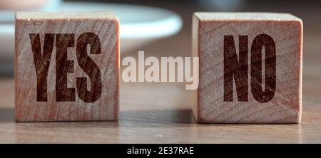 Ja versus keine Holzwürfel vor dem Kakaobecher auf dem Holztisch. Geschäfts- oder Karriereentscheidungskonzept. Stockfoto