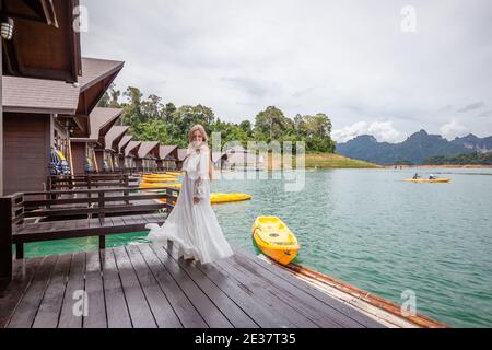 Travel Woman steht am Pier von Wooden House am See Mit tropischen Bergen Stockfoto