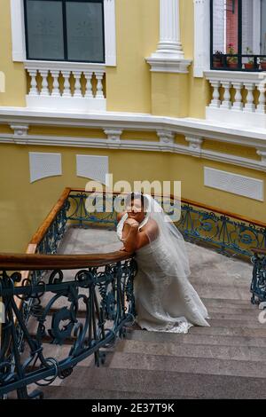 Braut posiert, Steintreppe, Blick von oben, dekoratives Geländer, elegantes Setting, Hochzeitsporträt, weißes Perlengewand, Schleier, Südamerika, Quito, Stockfoto