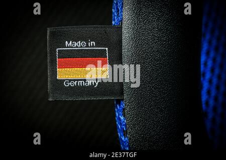 Extreme Nahaufnahme eines Made in Germany Labels mit deutscher Flagge, auf schwarzem Stoff genäht. Makrofotografie. Stockfoto