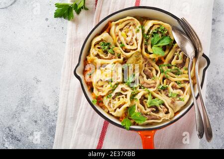 Fleischteigbrötchen mit Fleisch oder Faulknödeln in alter roter Gusseisenpfanne auf rustikalem grauen Hintergrund. Draufsicht. Stockfoto