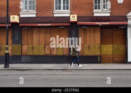 Die Menschen gehen an einem geschlossenen Restaurant in Soho, London, während der dritten nationalen Coronavirus-Sperre in England vorbei. Stockfoto