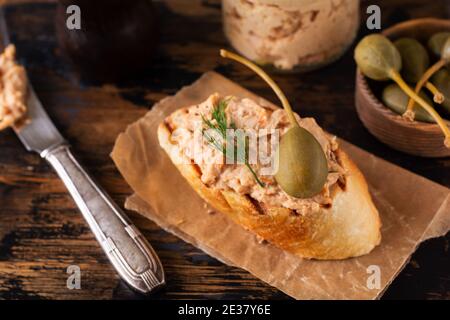 Sandwich mit leckeren hausgemachten Hähnchenpastete mit Gewürzen und Dill In einem Glas und eine Scheibe Brot in der Nähe Und Kapern serviert im Vintage-Stil auf alt Stockfoto