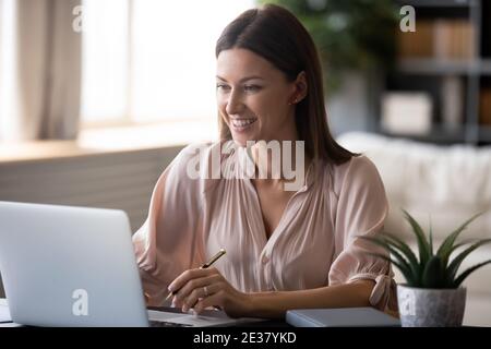 Nahaufnahme lächelnde Frau, die schnurlose Ohrhörer mit einem Laptop trägt Stockfoto