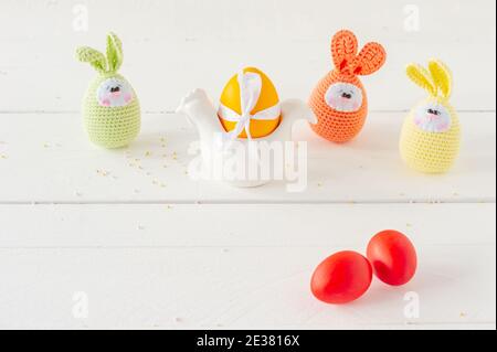 Arrangement Dekoration Frohe Ostern Urlaub Hintergrundkonzept. Ostereier mit handgestrickten Eiern auf weißem Holztisch. Pastellfarben Stockfoto