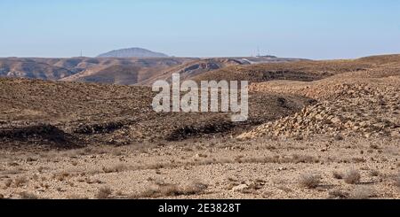 Eine zerklüftete, gebirgige Wüstenlandschaft westlich des makhesh ramon Krater mit einem israelischen Grenzposten und Kamelbuckel Im sinai Stockfoto