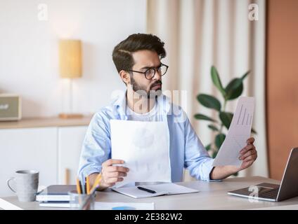 Junger Arabischer Geschäftsmann, Der Mit Papieren Am Schreibtisch Im Büro Arbeitet Stockfoto