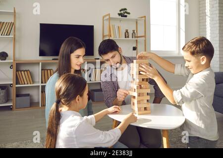 Konzentrierte Eltern und Kinder spielen Jenga, während sie ihre Freizeit genießen Zu Hause Stockfoto