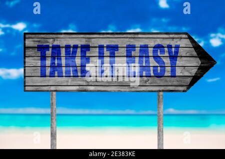 Take IT Easy Holzschild mit auf einem Strand Hintergrund Stockfoto